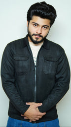 Man wearing a black jacket and blue pants against a white background