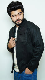 Man wearing a black jacket over a white shirt with a plain background