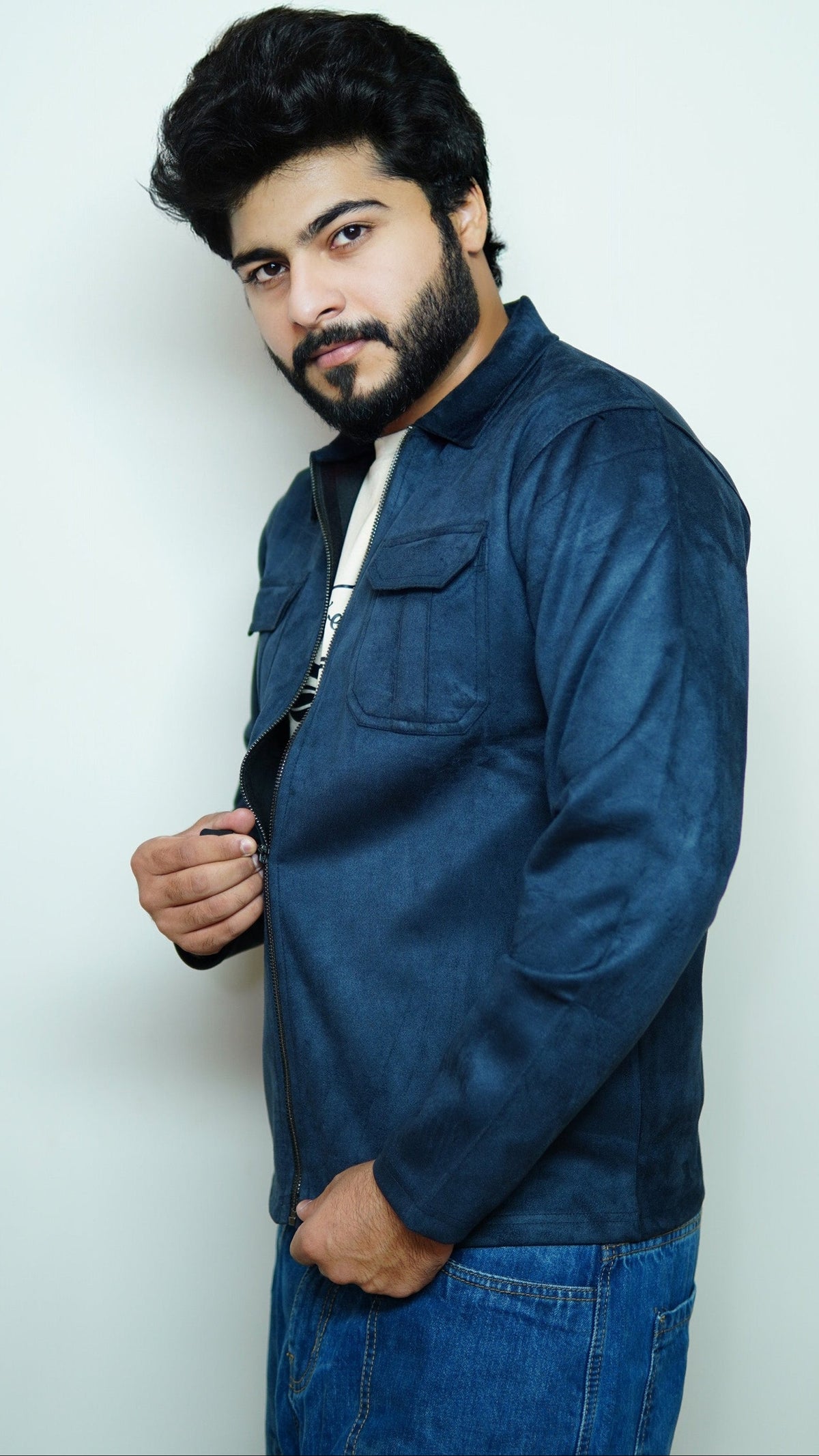 Man wearing a blue jacket and jeans against a white background