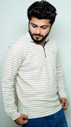 Man wearing a striped sweater and blue jeans against a light background